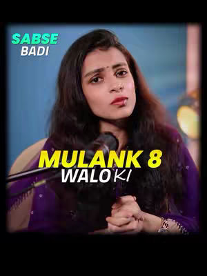 The cover image features a woman with long, dark hair, wearing a purple outfit and a small bindi on her forehead. The text overlay is in yellow lettering on a dark gradient banner, with the words "MULANK 8 WALO KI". Above that is text in a green box that reads "SABSE BADI". The woman is positioned in front of a dark background, with a microphone in front of her. The overall color palette appears dark with a mix of purples, yellows and greens.