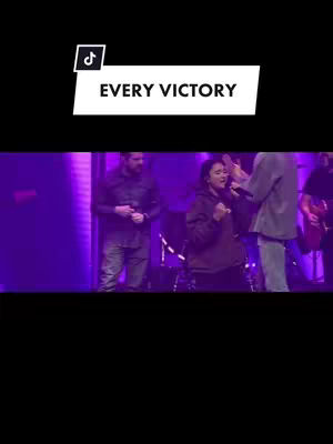 The cover image shows a live performance on a stage, with individuals singing and playing instruments. The setting has dim lighting with purple hues. The image also includes a text overlay with the words "EVERY VICTORY".