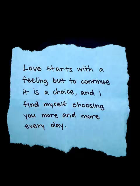 The image showcases a light blue, torn piece of paper against a black background. The paper has a rough, uneven edge and is centrally positioned. Handwritten in black ink are the words: "Love starts with a feeling but to continue it is a choice, and I find myself choosing you more and more every day."
