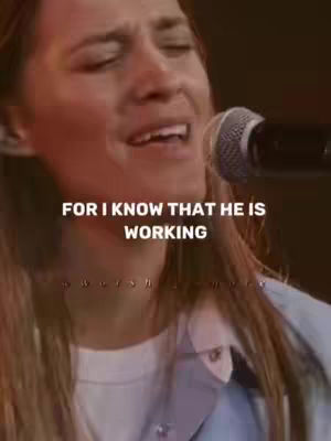 Close-up shot of a woman singing with a microphone, with overlaid text. The woman appears to be in a performance setting, possibly a church or concert. The background is blurred, with focus on her face.