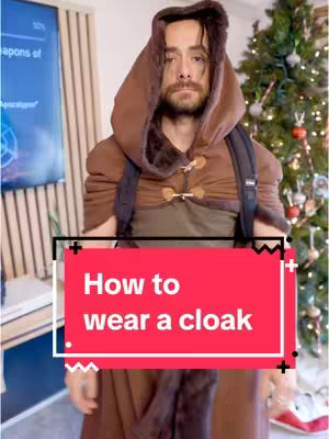 A man in a brown hooded cloak with a red text overlay. A Christmas tree is in the background.