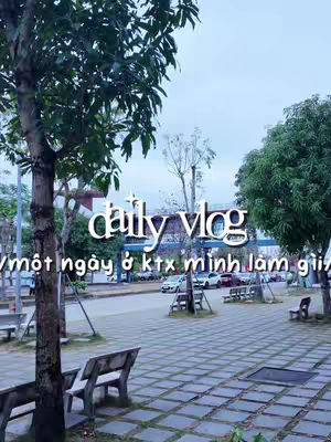An outdoor shot featuring a paved area interspersed with trees and benches. Overlayed text in white announces 'daily vlog' with a Vietnamese phrase below.