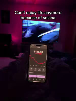 The cover image shows a dimly lit bedroom scene. In the foreground, a smartphone displays a financial app with a declining red graph and a current value of $126.40. The phone is angled, suggesting it's being held or resting on a surface. The background features a television screen showing blurred content and a wall illuminated with pink light. The overall composition evokes a sense of unease and potential financial stress.