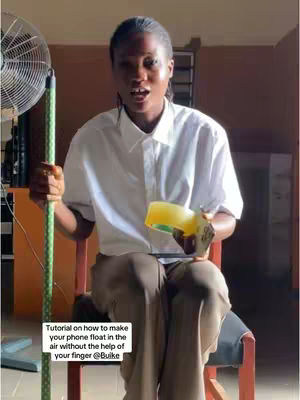 The cover image shows a young woman sitting on a chair, holding a green stick and a yellow object. She has her mouth open as if speaking. The background includes a fan and a wall.
