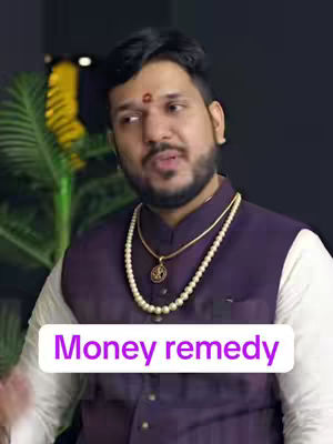 A man with a beard wearing a purple vest over a white shirt, and gold jewelry. The background is dark with a glimpse of a yellow and green object on the left. A text overlay reads "Money remedy".