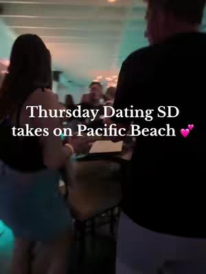 A scene inside a bar or event, with a somewhat blurry background of people conversing. The foreground features the backs of two people, a woman on the left in a light-colored top and denim skirt, and a person on the right wearing a black garment. Text overlayed on the image promotes an event called "Thursday Dating SD" in Pacific Beach