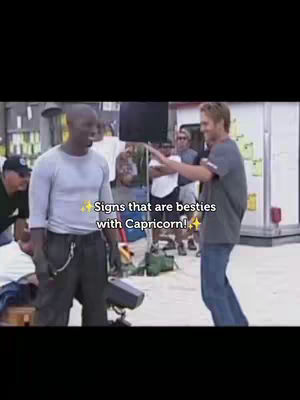 The cover image is a vertical video shot. It features a scene from a presumably filmed movie. The layout focuses on two men in the foreground, with other people and equipment visible in the blurred background. The core of the image is the text overlay reading 'Signs that are besties with Capricorn!'