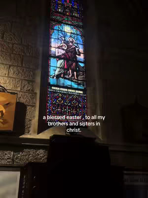 The cover image features a high-angle shot inside a church, focusing on a large, ornate stained-glass window. The window is the central element, depicting a religious scene with figures in robes and vibrant colors. Light streams through the glass, illuminating the scene. The overall composition is symmetrical and peaceful, with the dark interior setting off the bright window.