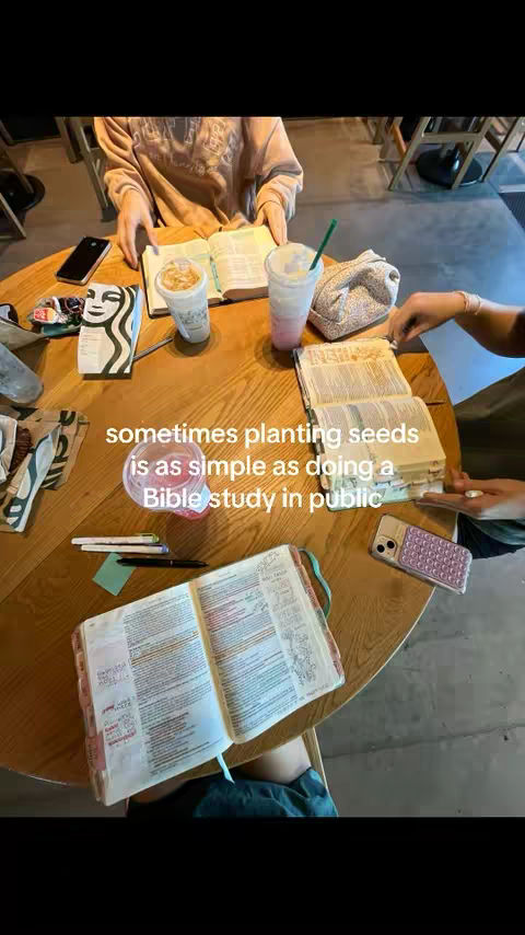 A medium shot captures a wooden table in a coffee shop setting, occupied by various items. Two open Bibles lie on the table, near two cups of coffee and a Starbucks cup with a logo, suggesting a Bible study session. A phone and pens add to the scene. The caption "sometimes planting seeds is as simple as doing a Bible study in public" is laid over the image and the color palette is neutral and warm.