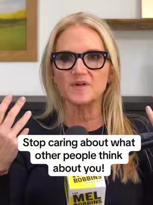 A woman with blonde hair and glasses is in the center of the frame, speaking into a microphone. Overlayed text urges viewers to stop caring what others think. The background is slightly blurred and includes elements of a studio setting.