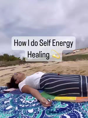 A woman, lying on a patterned blanket by the beach, is the focal point. Text overlayed on the image reads 'How I do Self Energy Healing' and has a cartoon-like drawing.