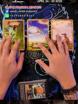 The image shows a top-down view of a tarot reading setup. Three tarot cards are face up, with hands of a person reaching towards them. Below the cards, a deck of tarot cards is visible. The background is a dark, patterned surface.