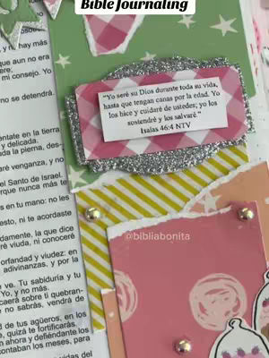 The image shows a page from a decorated bible with several layers of paper and text. The background is a light green color with small white stars. Overlaid on this is a piece of paper with a pink and white checkered pattern, on which a silver-bordered card contains text. Beneath this, there are other layers with various patterns, including stripes and polka dots. There are small metallic elements and text from the bible on the left.
