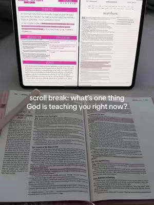 A bible study setup on a table. An open bible with notes highlighted in pink is in the foreground. A tablet displaying bible study notes on one side and the bible chapter on the other is in the background. A pink pen is visible next to the bible. The overall composition is well-lit and focused on religious study.