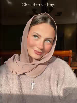 The cover image shows a woman looking up with a light pink veil covering her head and shoulders. She is wearing a pink sweater and a silver cross necklace. The background is blurred, suggesting an indoor setting with sunlight.