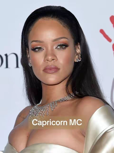 A close-up shot features Rihanna, with a soft, neutral-toned makeup look. She poses directly towards the camera, with a slight, subtle expression. The photo has an elegant feel, with soft lighting emphasizing her features. A text overlay identifies the subject as Capricorn MC.