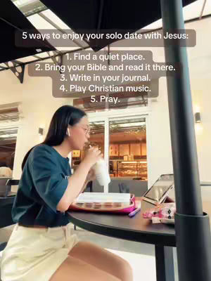 The cover image shows a woman sitting at a table, likely at a cafe or restaurant. She is holding a cup and looking down at it while sipping, with what appears to be a book or journal, a tablet, and some pink items are on the table. Text overlaid on the image lists "5 ways to enjoy your solo date with Jesus." There is a view of a bakery-like establishment in the background.