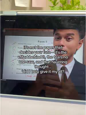 A man in a suit jacket is filmed in front of a screen that contains a form 5 assignment. A text overlay appears in the center of the video on the screen. The man looks directly at the camera as if he is addressing the audience directly, with a mix of concern and frustration etched across his face. The background features a whiteboard or a display, with the man in the foreground.