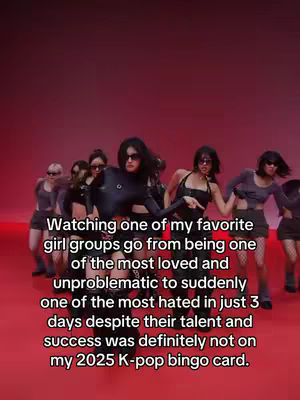 A group of women stand in a line, wearing sunglasses and holding poses. The background is a solid, bright red color, suggesting a studio or performance setting. The image has a sense of dynamism.