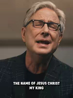 The cover image shows a man wearing glasses, focusing intently on a point off-camera. The man is of older age, has white hair, and is wearing a dark blazer over a black shirt. Text overlayed at the bottom reads, 'THE NAME OF JESUS CHRIST MY KING,' in a bold, white font.