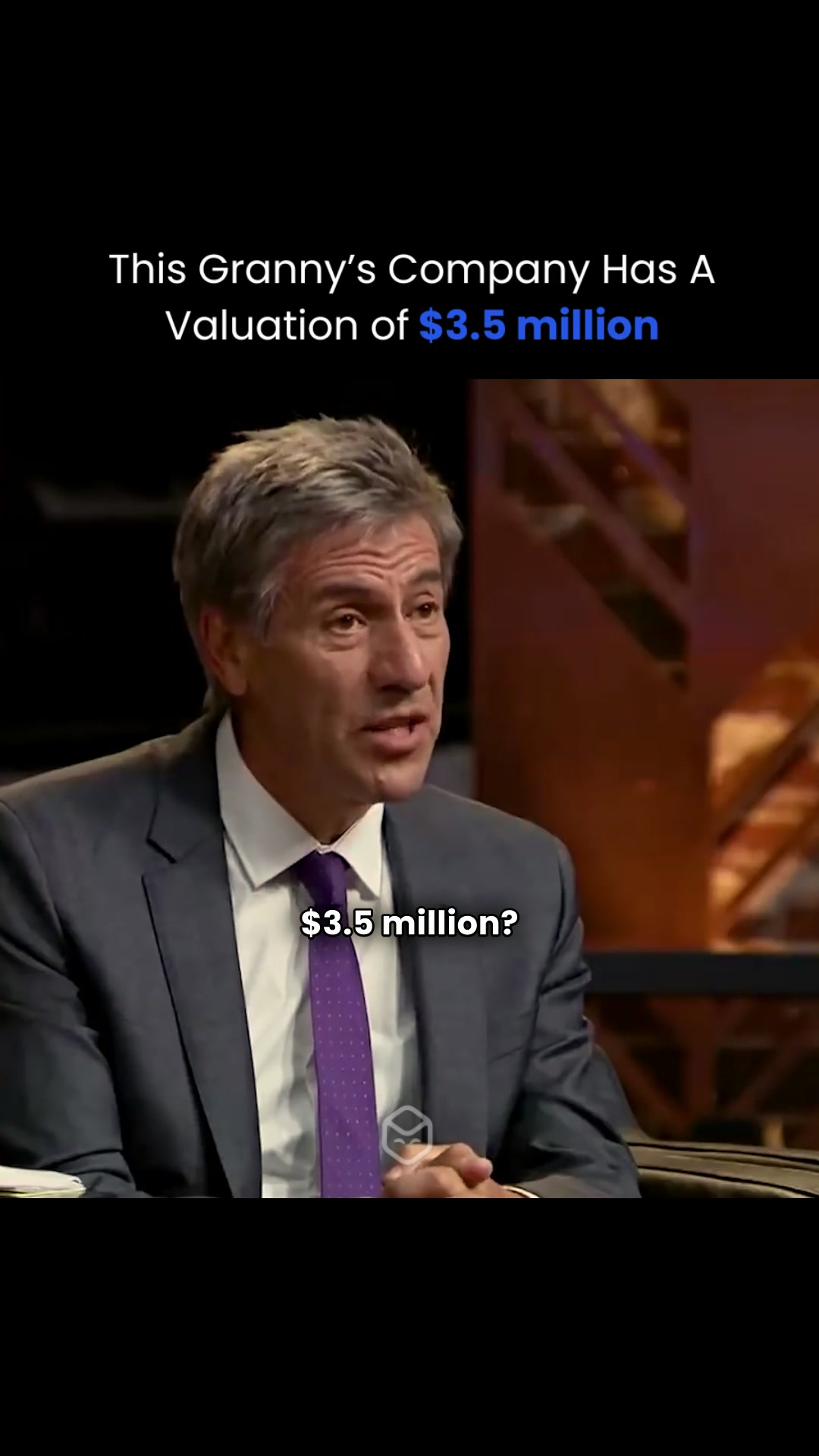 A medium shot capturing a man in a suit, angled slightly to his left. He is speaking, with a serious expression, indoors, likely in a TV studio.