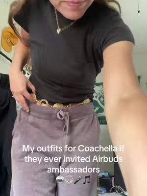 The image is shot from a slightly low angle, featuring a person's mid-section. The person is wearing a black t-shirt, a gold chain is visible around their neck. They are also wearing purple corduroy pants with a gold chain belt. Text appears at the bottom of the image.