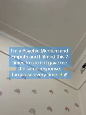 A light-toned photo depicting a room corner, mostly empty with a wall decorated with pastel rainbow decals. A light blue rectangle with white text floats on the left side of the frame near the top, detailing the creator's experience with their empathic abilities, a psychic medium and an answer to a question, with the phrase 'Turquoise every time' at the end. The ceiling appears very neutral, painted off-white, the walls similarly hued. A subtle ceiling trim outlines the structural corner.