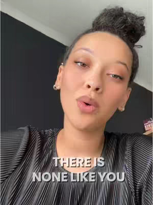 A woman with her hair up in a bun is looking slightly up and to the left with a close up shot and her mouth slightly open. Overlayed on the bottom of the image is white text with a black shadow. The background is black.