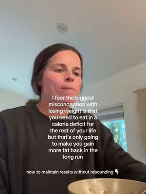 A woman looks up at the camera, with text overlays describing the video's topic. She has brown hair and wears a dark grey sweatshirt. The background is a domestic indoor setting, with a partial view of a bowl in the lower foreground.