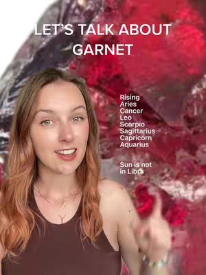 A woman with light brown hair and a brown top is looking at the camera, speaking while pointing to her right. Behind her is a blurred background of what looks like gemstones and text. Text overlays read 'LET'S TALK ABOUT GARNET' and a list of zodiac signs and a statement about Libra.