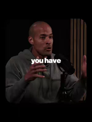 A man with a shaved head, wearing a gray hoodie, is speaking into a microphone in a studio setting. A white text overlay at the center reads "you have." The background is dark with vertical wooden paneling.