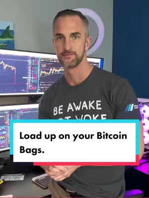 A man stands in front of multiple computer screens displaying stock charts, with a text overlay at the bottom. The man is wearing a dark t-shirt with white text. The background includes a blue wall and a ring light.