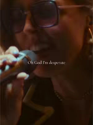 Close-up shot of a person, likely the creator, holding a microphone, with text overlaid. The person is wearing sunglasses.