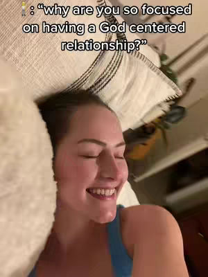 A woman is lying in bed, appearing to be resting her head on a white pillow, with the top of her body visible, including her face and the top of her chest partially wearing a blue sleeveless top. The woman has her eyes closed, and a slight smile is on her face. Text is overlaid in the top left corner asking a question . The background is dimly lit, revealing a bed. The overall composition is intimate and personal.