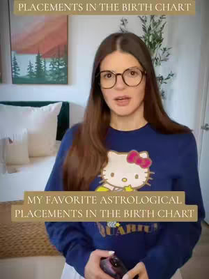 A woman with long brown hair and glasses is standing in front of a bed. She is wearing a dark blue sweater with a Hello Kitty design. Text overlays appear at the top and bottom of the image.