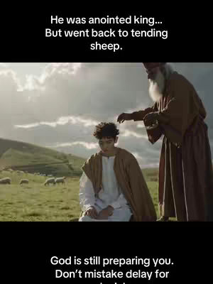 The image shows a scene from a biblical story. In the foreground, a young man kneels. He is wearing a white tunic and a brown cloak. An older man with a long white beard stands over him, his hand extended as if blessing the young man. In the background, a green field with some sheep and rolling hills are visible. The sky is overcast or cloudy.