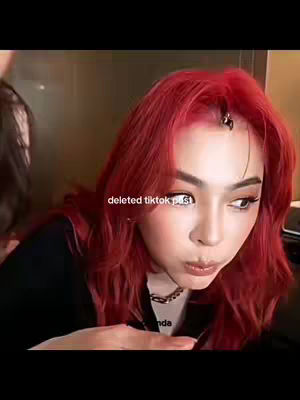 A close-up shot features a woman with bright red hair and visible eye makeup, looking at the camera with a slight pout. Text overlayed on the image reads 'deleted tiktok post'. The background is blurred, suggesting an indoor setting.