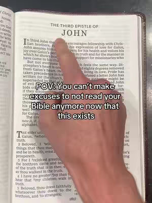 The image shows the open pages of a Bible with a hand pointing at a passage and overlaid text. The lighting appears natural and the composition is straightforward, focusing on the book's pages and the hand gesture.