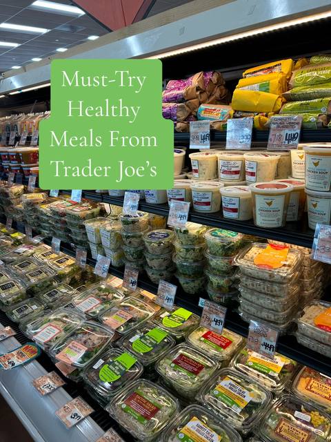 A well-lit photograph captures an array of pre-made Trader Joe's meals neatly arranged within a refrigerated display. The image is filled with various prepared food items in clear plastic containers. The products line the shelves of a grocery store setting, under bright overhead lights. In the foreground, there's a mix of salads, sides, and prepared meals. The color scheme is dominated by the vibrant colors of the food products, from healthy green salads to a wide assortment of ingredients. The layout is a straightforward view of the product display, emphasizing the visual appeal and convenience of the ready-to-eat meals.