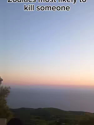 The image shows a scenic view at what seems to be the end of the day. The sky gradients from a light blue at the top to a rose and orange hue at the bottom. Below the sky, a dark mass of land is visible, with a body of water stretching to the horizon. The top left corner shows the corner of structure, possibly a building or a wall.