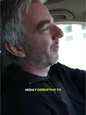 A man with grey hair is driving in a car, viewed from a side angle. The image has a slightly blurred background, suggesting motion. Text is overlaid on the bottom of the image.
