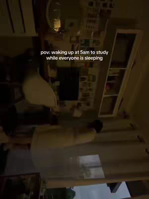 The cover image shows a room illuminated by warm, yellowish light, likely at dawn or dusk. The scene, which is in vertical format and appears to be a view from inside the room, has text overlayed. The room layout includes a light fixture, what appears to be a white shelf unit filled with items that are obscured. The composition suggests a casual or intimate setting.