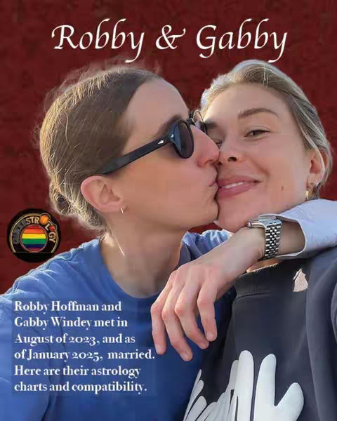 The cover image features a warm, intimate moment, with two women sharing a kiss. The focus is on their faces, with one woman gently kissing the other on the cheek. The background has a deep red color. Text in a stylized font is added over the image, which reads "Robby & Gabby."