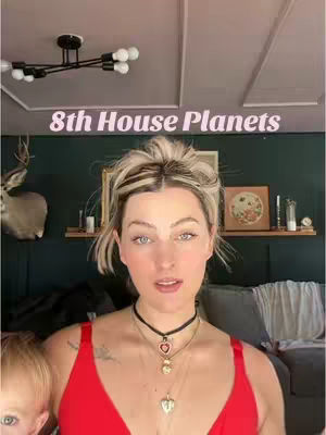 A woman with blonde hair and a red top looks directly at the camera, with the text overlayed. In the background, there's a deer head mount, dark green wall and small decorative items. A small child is visible on the left.