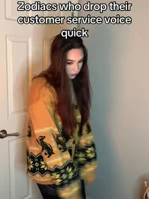 A woman with long brown hair is standing in what appears to be a doorway. She is wearing a yellow sweater with a design featuring a black animal, possibly a bear, and black and yellow decorative elements. The text overlay "Zodiacs who drop their customer service voice quick" is at the top.