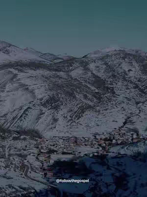 A high-angle shot showcases a snowy mountain range and a small village nestled below. The scene is dominated by shades of gray and white, representing the snow-covered landscape. A teal gradient is used in the sky, giving depth to the scene. The overall composition is cold and serene, with a sense of isolation.
