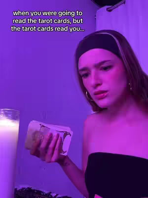 A woman with a serious expression holds a deck of tarot cards, illuminated by a soft, purple light. Overlay text introduces the theme of the tarot cards reading the user.
