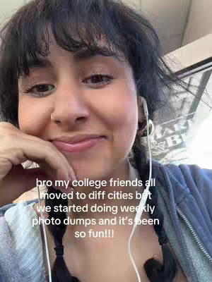 A close-up selfie of a woman with dark hair, wearing a blue top, and earbuds. The background is blurred. Overlayed text says she and her college friends do weekly photo dumps.