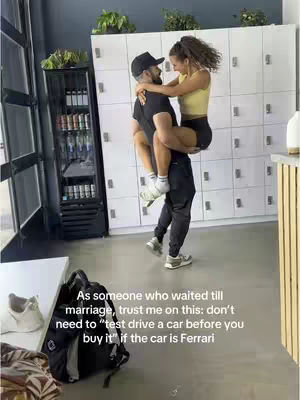 A photo of a man holding a woman in his arms, smiling. The man is wearing a black cap and t-shirt, and the woman is wearing a yellow top and black shorts. They appear to be in a gym or a similar setting. There's text overlaid on the photo.