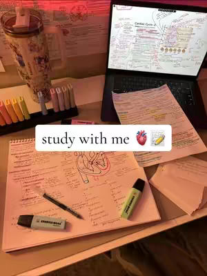 A study setup featuring a laptop displaying notes, an open notebook with notes and diagrams on subjects, a pen, highlighters, and a cup or tumbler. The scene is lit with warm tones, suggesting an evening or indoor study environment. The hook 'study with me' appears on the image.